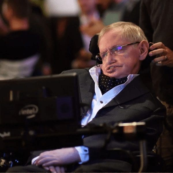 stephen hawkins seated in powerchair with monitor