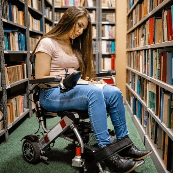 woman with Friedreich Ataxia in library seated in a powerchair