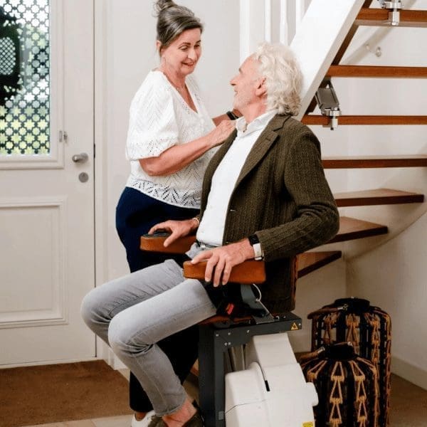 man on a stairlift smiling at woman at home