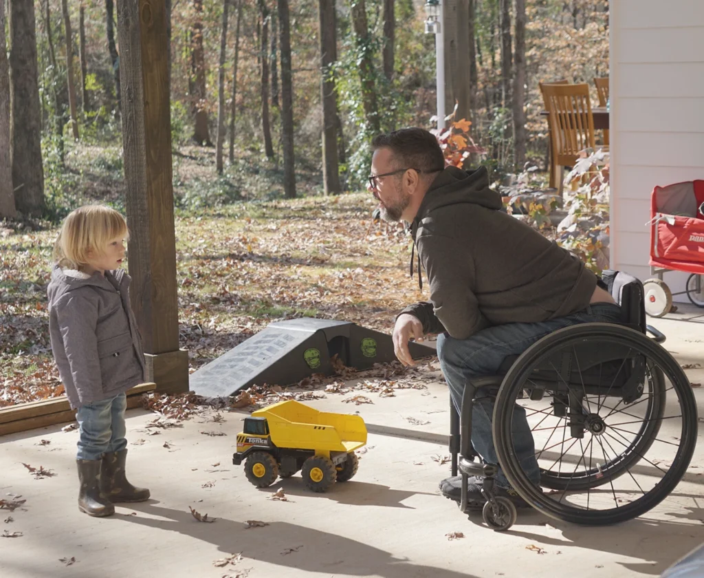 Man in motion composites manual wheelchair talking to child